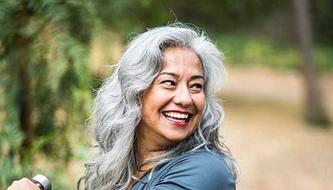 A smiling middle-aged woman exercises outside.